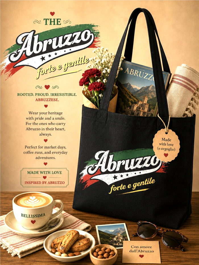 Black tote bag with 'Abruzzo' branding on a wooden table with coffee, cookies, and flowers.