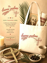 White tote bag with 'buone palme' design, palm leaves, and religious book on a wooden surface.
