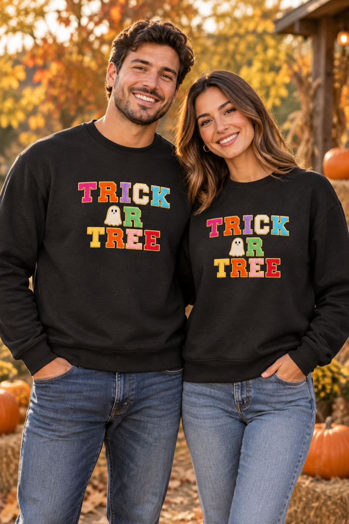 Couple wearing black Trick or Tree Halloween sweatshirts in an autumn setting
