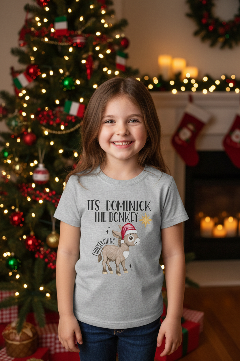 Five-year-old girl wearing the Dominick the Donkey shirt beside a Christmas tree