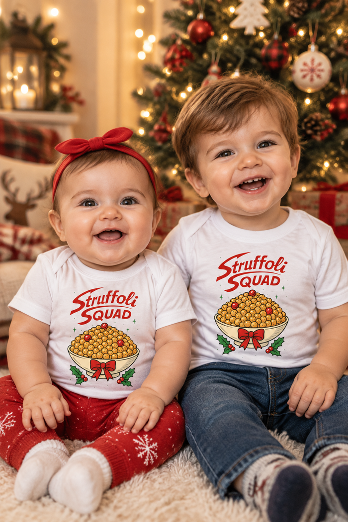Two babies in Struffoli Squad shirts by the Christmas tree