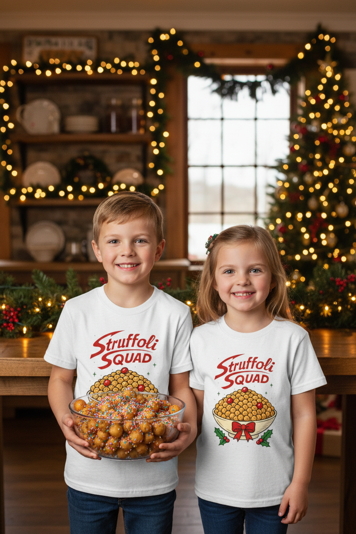 Two kids in white Struffoli Squad shirts holding a bowl of struffoli in a Christmas-decorated Italian American kitchen
